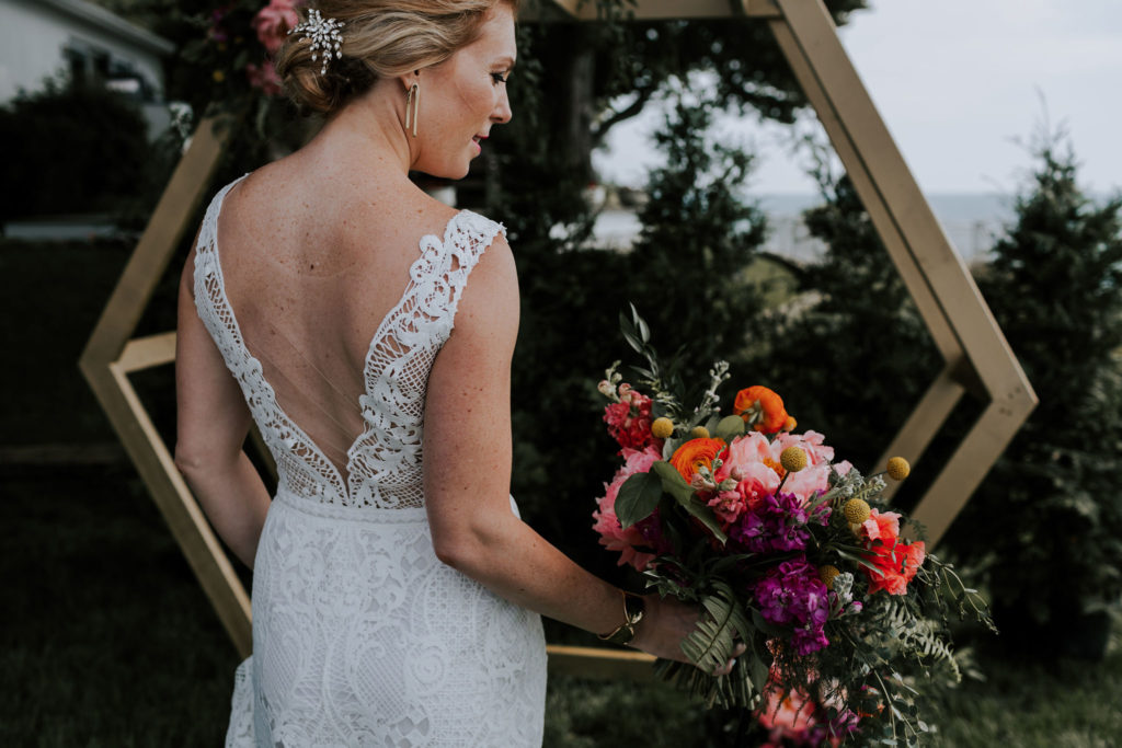Bride holding colorful bouquet by hexagon arch